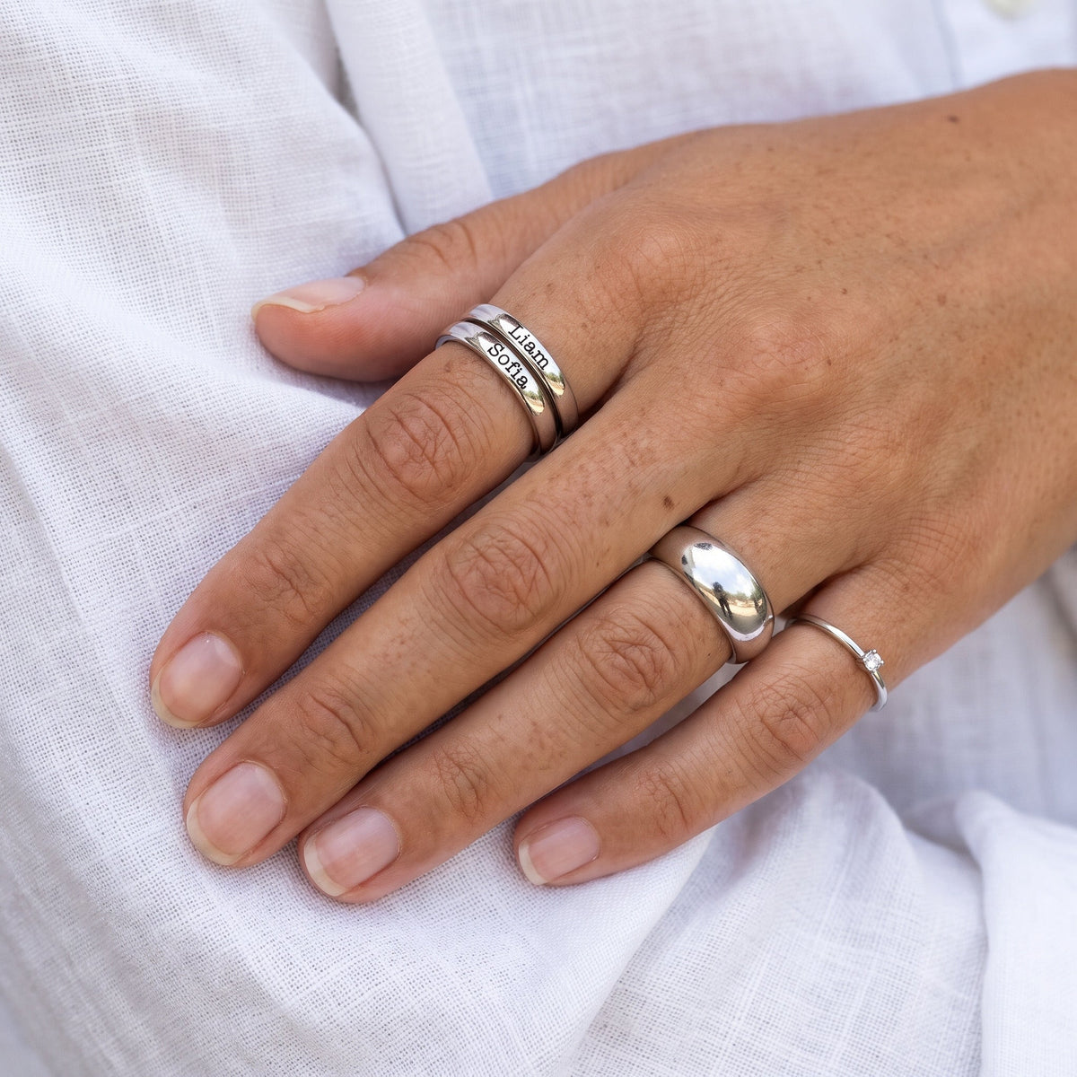 Bague fine empilable avec prénom – argent – associée à d’autres bagues, portée, gros plan